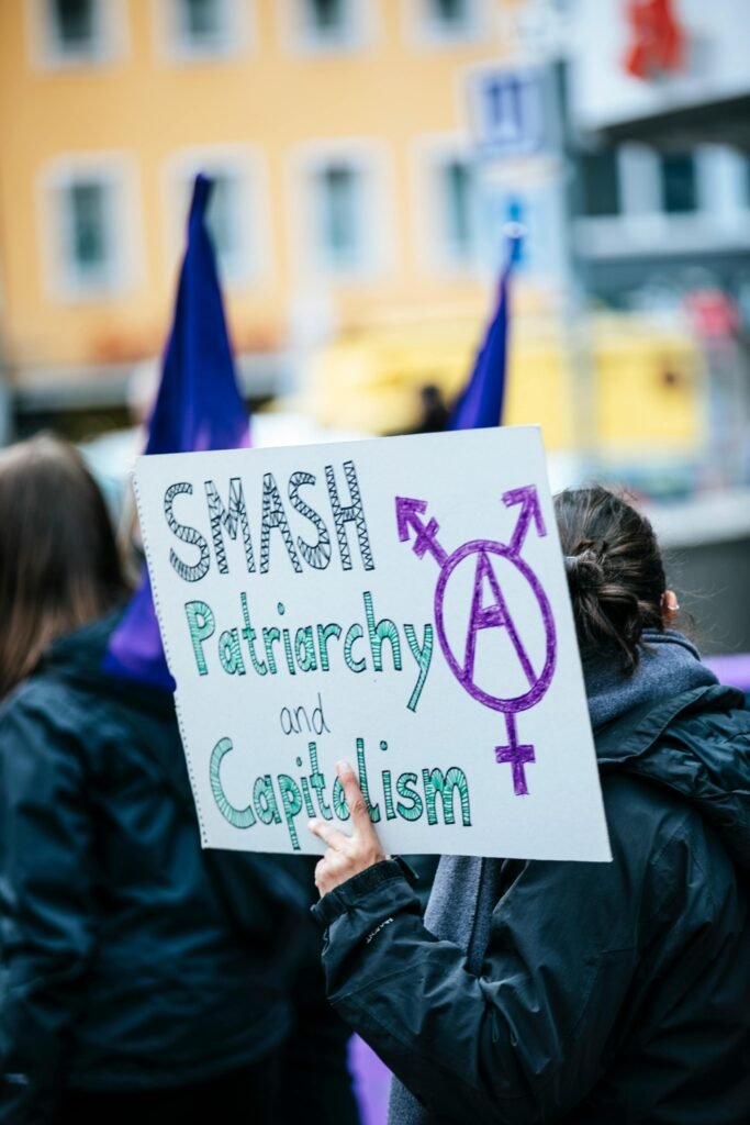 A Millennial Woman Holding Smash Patriarchy and Fuck Capitalism Placard