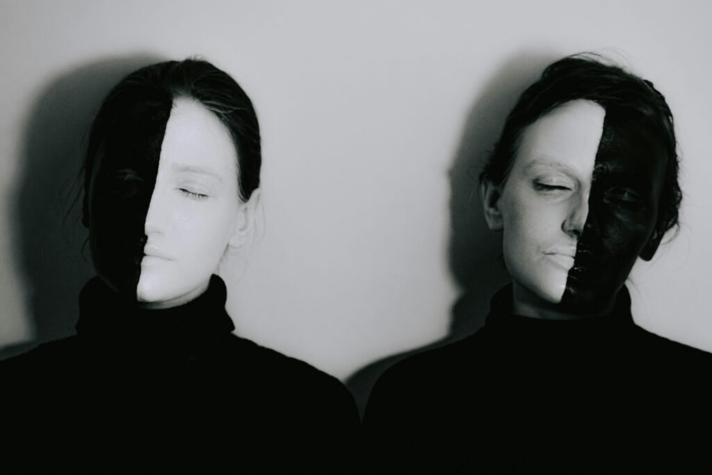 Black and white of women with face painted in contrast black and white colors standing with closed eyes against white background